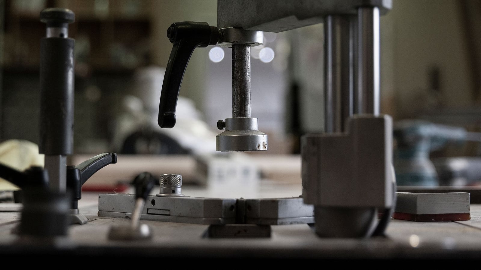 Bookbinder's tools: a press, cutting blade, and ruler arranged on a workbench.