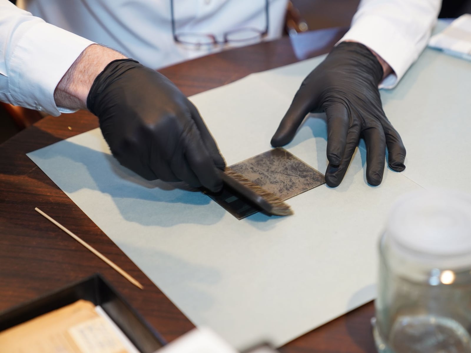 Hands of a conservator repairing a page of an old book using Japanese tissue paper.