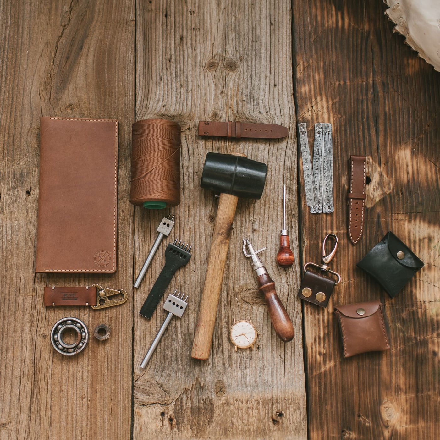 A stack of handmade A5 leather notebooks in various natural colors on an oak table.